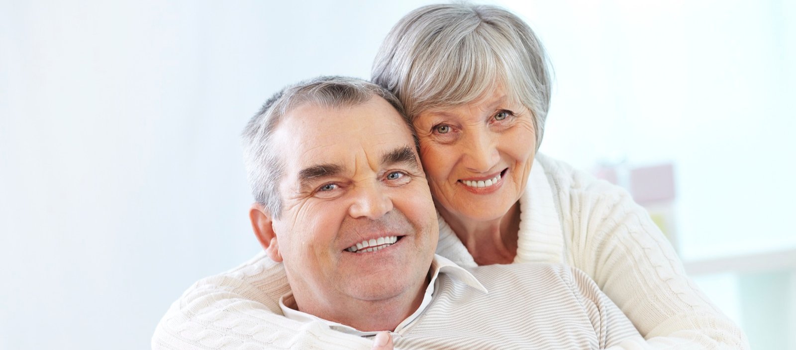 Casal idoso sorrindo após tratamento odontológico na Dent & Dent